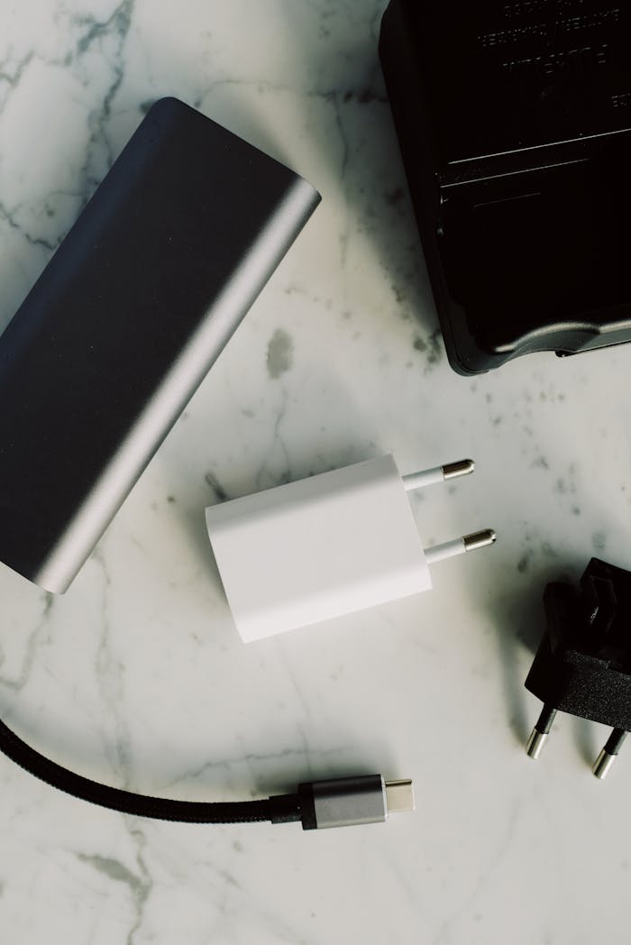about-us Composition of various modern charging units with adapter and small black external battery pack with short cable placed on white marble table